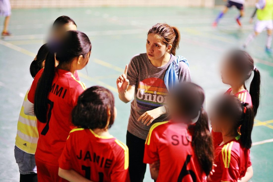 Paulina coaching a huddle of young soccer players