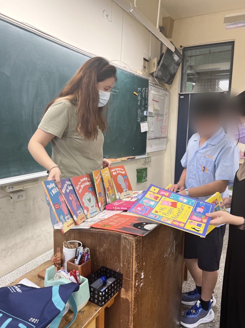 Paulina laying out English picture books on a desk with students