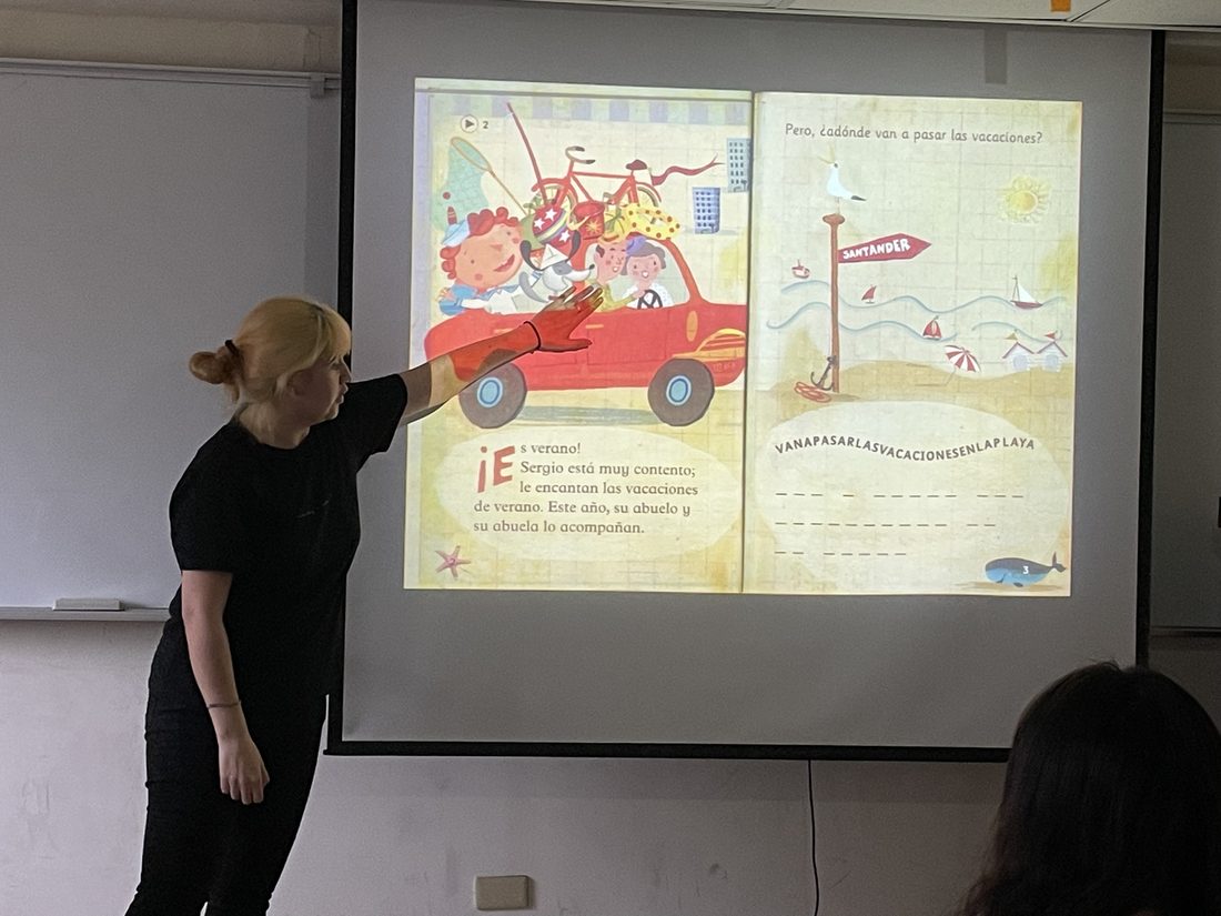 Paulina pointing at a Spanish graded reader projected on a screen